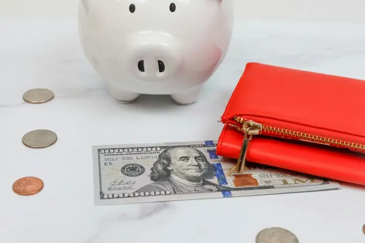 Celengan, dompet, dan uang di atas meja